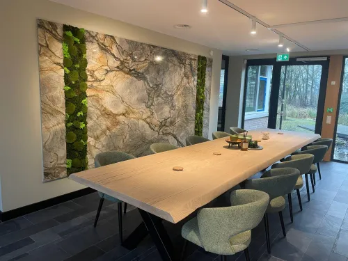 Stijlvolle vergaderruimte met lange houten tafel, comfortabele stoelen en decoratieve groene wandpanelen.