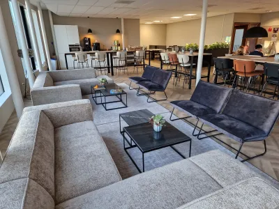 Loungegedeelte in de personeelskamer met comfortabele hoekbank en fauteuils.