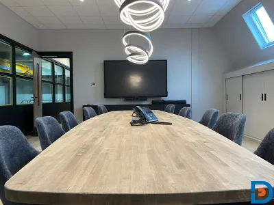 Moderne vergaderruimte met lange tafel, comfortabele stoelen en stijlvolle verlichting, geschikt voor zakelijke bijeenkomsten.