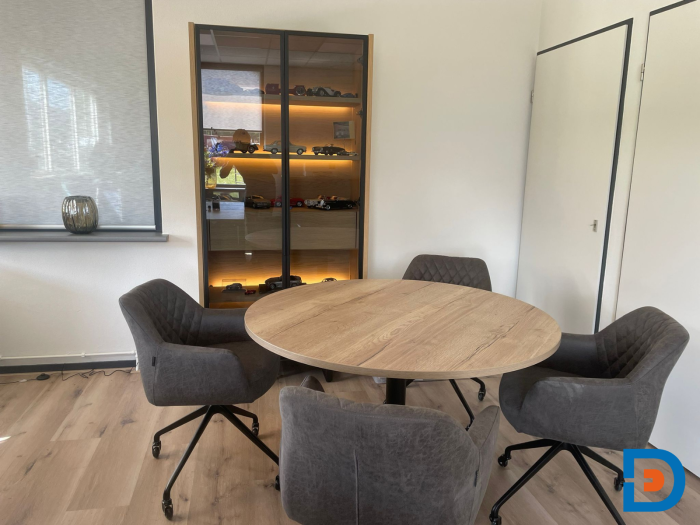 Moderne kantoorinrichting met een houten kast en een vergadertafel met comfortabele stoelen. De kast biedt opslagruimte en de vergadertafel is perfect voor samenwerking en vergaderingen in een professionele omgeving.
