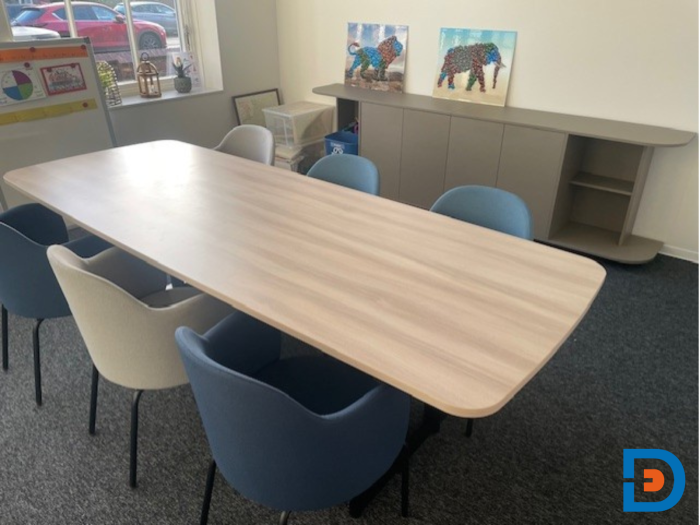 Vergadertafel met houtlook blad en kuipstoelen op vierpoots onderstel.