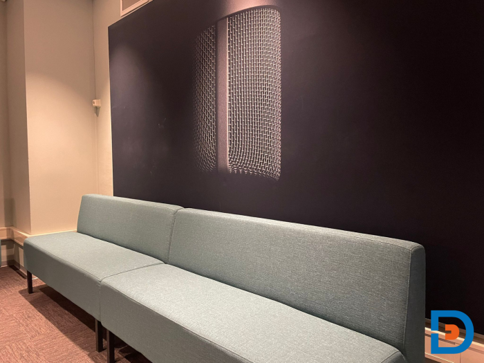 Langwerpige zitbank op maat in een akoestisch ingerichte studiohoek met warme verlichting,