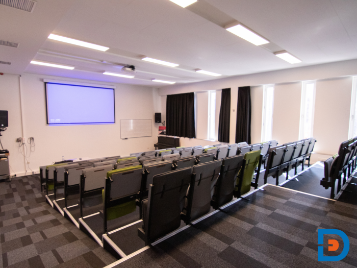 Trapgewijs geplaatste kleurrijke klapstoelen in collegezaal met opvallende wandafbeelding