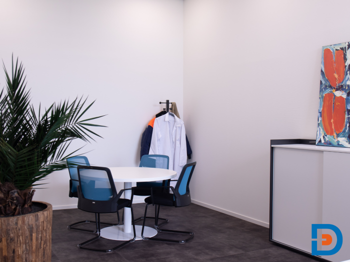 Moderne kantoorruimte met ronde vergadertafel en vergaderstoelen voorzien van kleurrijke netbespanning.