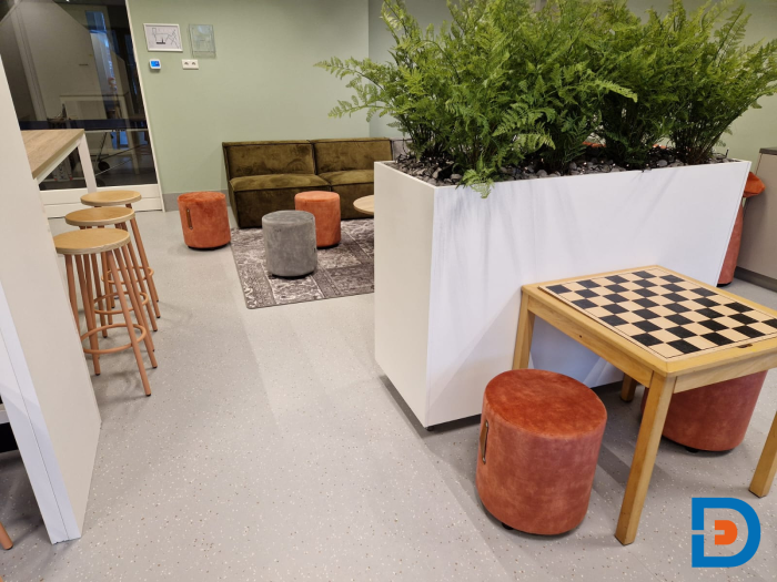 Kindvriendelijke zithoek met plantenbak, schaaktafel, krukjes en zachte kleuren in de kinderopvang in Geesteren.