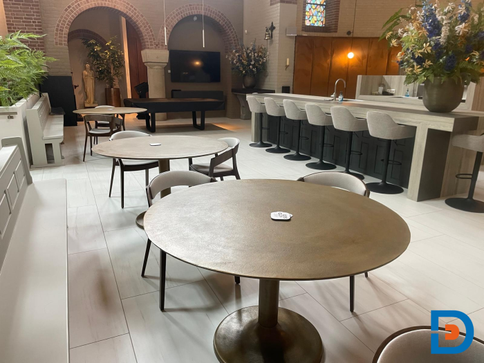 Hergebruikte kerkbanken gecombineerd met moderne tafels en stoelen voor een unieke mix van klassiek en eigentijds