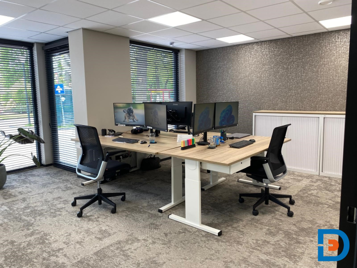 Lichte kantoorruimte met glazen wanden, pvc- en tapijtvloeren en aantrekkelijke werkplekken.