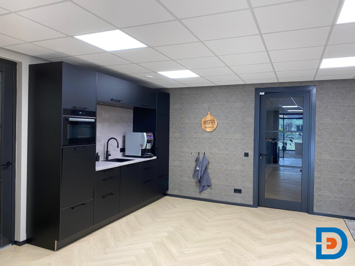 Functionele maatwerkkeuken gecombineerd met sfeervol behang en een elegant visgraatpatroon in PVC-vloer.