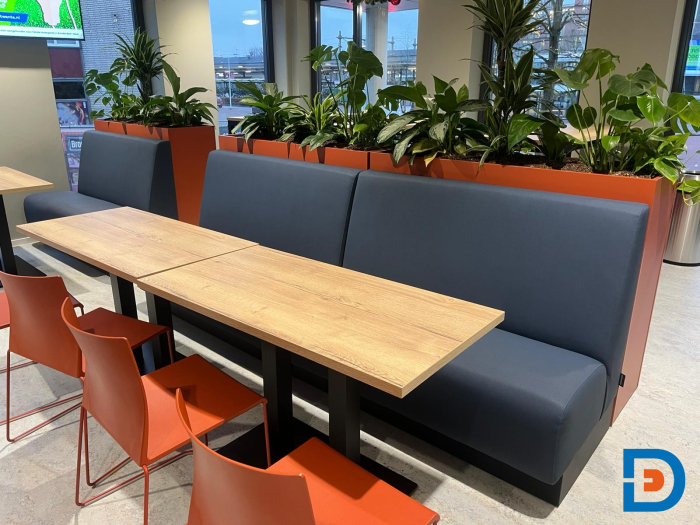 Moderne kantine met een treinbank, comfortabele stoelen, en een plantenbak voor een ontspannen en informele sfeer bij ROC Almelo.