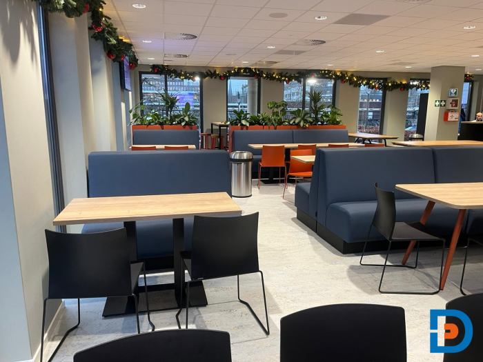 Kantine met comfortabele zitbanken en tafels, ingericht voor informele ontmoetingen en groepsmaaltijden bij ROC Almelo.