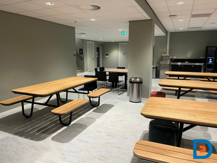 Moderne kantine met lange tafels en stoelen, ideaal voor informele vergaderingen en groepsmaaltijden bij ROC Almelo.