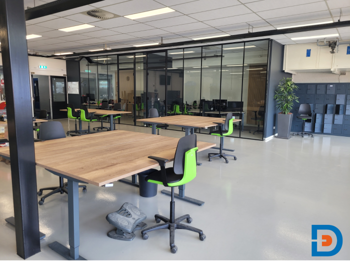 Praktische werkplaatsinrichting met verstelbare handslingerbureaus en comfortabele werkstoelen.