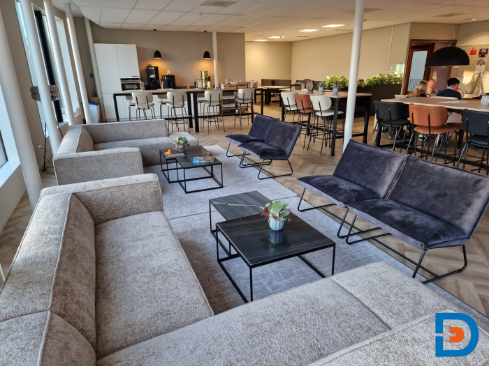Loungegedeelte in de personeelskamer met comfortabele hoekbank en fauteuils.