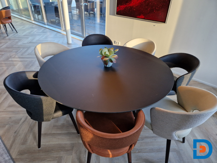 Ronde tafel in personeelskamer met comfortabele kuipstoelen, gestoffeerd in kunstleder en bouclé stof.