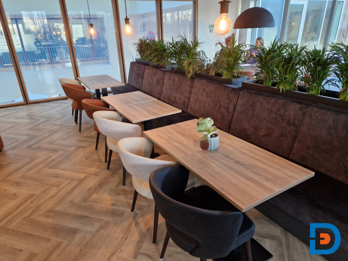 Treinbank met kolomtafels en bijpassende kuipstoelen, aangevuld met op maat gemaakte plantenbakken met groene beplanting