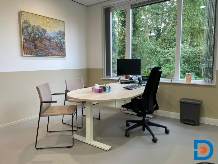 Lichte huisartsen behandelkamer met fijne werkplek en warme, rustgevende kleuren.