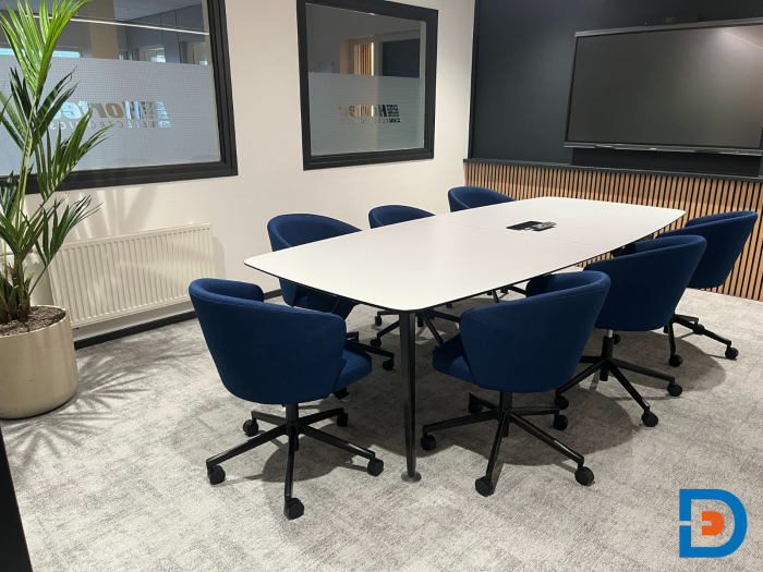 Vergaderruimte met grote vergadertafel en ergonomische stoelen.